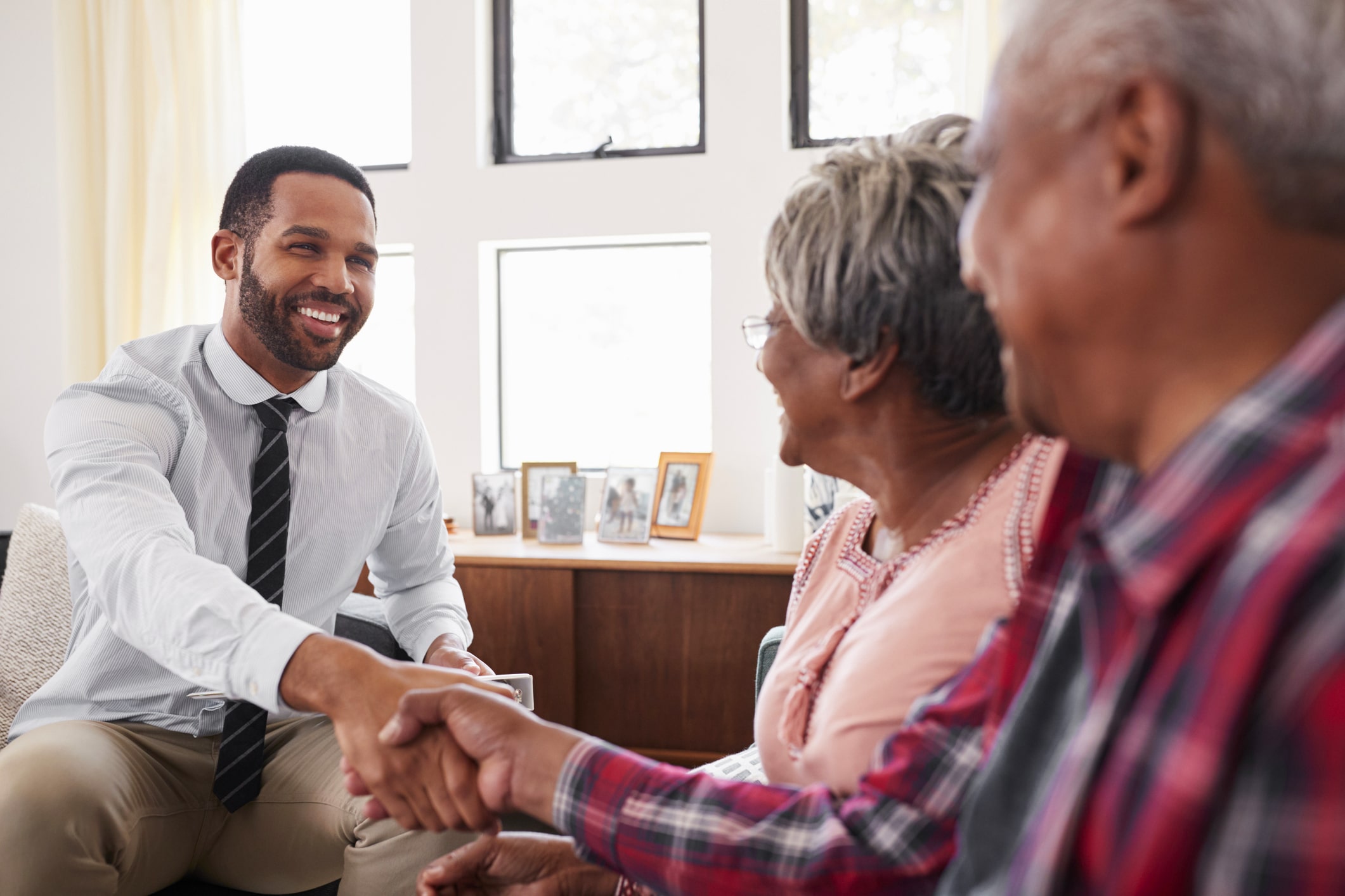 Senior Couple Shaking Hands With Male Financial Advisor At Home
